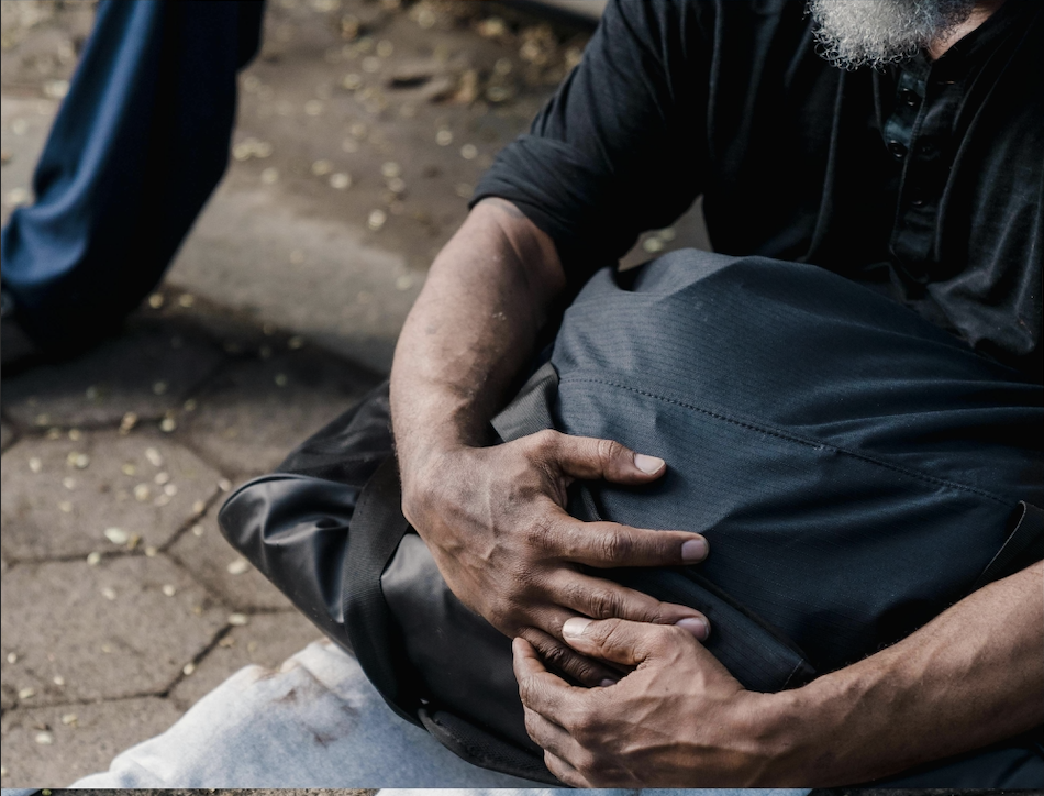 Man on sidewalk holding a bag 