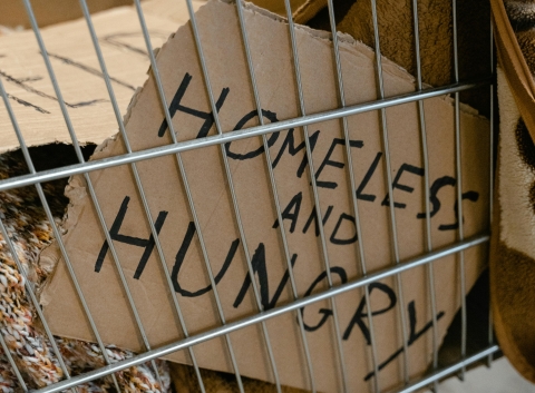 Image of a placard reading 'Homeless and Hungry' placed in a cart.