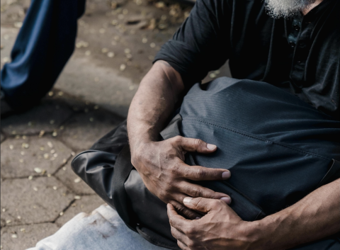 Man on sidewalk holding a bag 