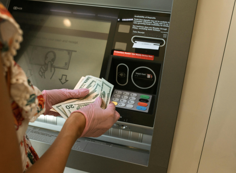 Person at ATM, holding money
