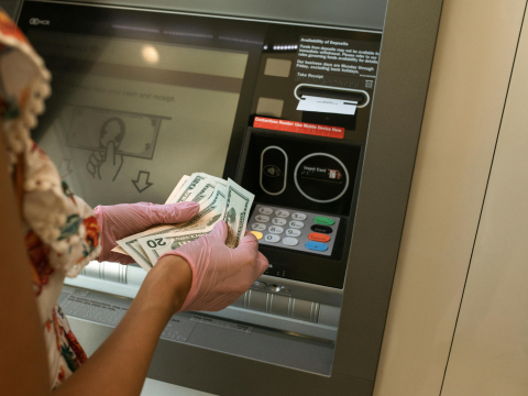 Person at ATM, holding money