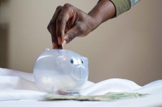image of hand dropping coin in piggy bank